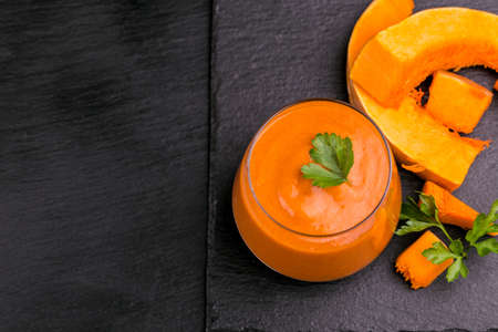 Fresh pumpkin smoothie in glass with parsley on black slate background. Top view. Copy spaceの写真素材