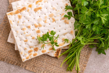 Traditional Jewish kosher matzo with bunch of fresh parsley on rustic burlap napkin. Copy spaceの写真素材