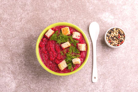 Bright tasty pureed beetroot soup in clay bowl. Healthy food concept. Gray marble background. Top view. Copy spaceの写真素材