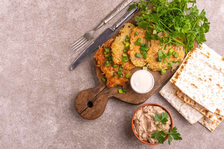 Tasty Hanukkah celebration food on vintage cutting board: homemade traditional potato, crunchy matzo, liver pate. Gray marble background. Top viewの写真素材