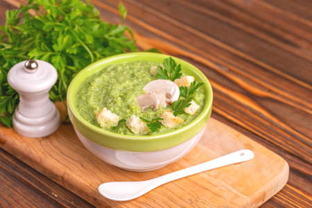 Fresh tasty pureed broccoli soup in clay bowl with ingredients on cutting board. Healthy food concept. Rustic wooden background. Horizontal view. Copy spaceの写真素材