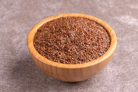 Raw flax seeds in wooden bowl on gray marble background. Copy space. Horizontal viewの写真素材