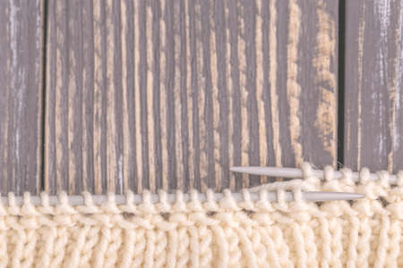 Warm knitted pattern of woolen yarn on gray rustic wooden background. Beggining of new handmade...