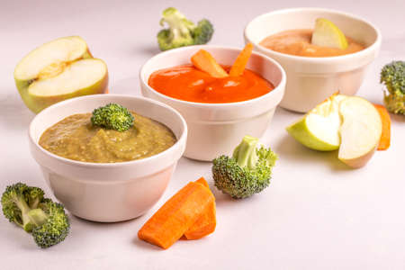 Variation pureed baby food in clay bowls with ingredients on white marble background. Copy spaceの写真素材