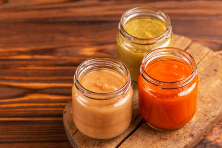 Variation pureed baby food in glass jars on vintage cutting board. Wooden background. Copy spaceの写真素材