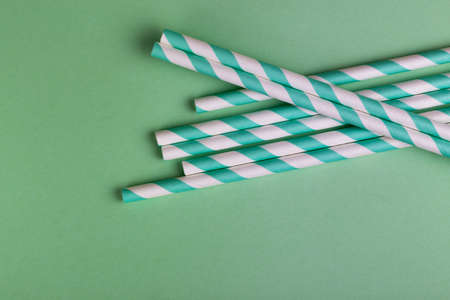 Colorful paper straws on bright green background. Event and party supplies. Earth pollution concept....