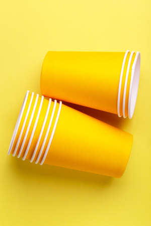 Recycling paper cups for drinks on bright yellow background. Copy space. Party and recycling conceptの写真素材