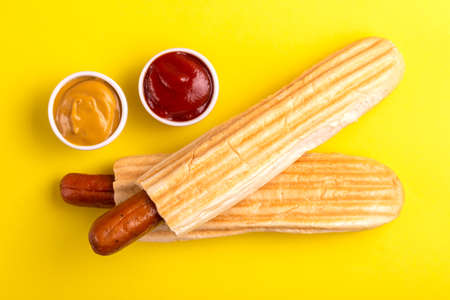 Two grilled french hot dogs with mustard and ketchup on bright background. Junk or fast food. Copy spaceの写真素材