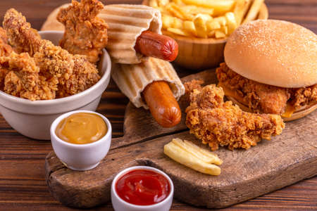 Delicious but unhealthy food with ketchup and mustard on vintage cutting board. Fast carbohydrates, junk and fast food. Warm wooden background.の写真素材