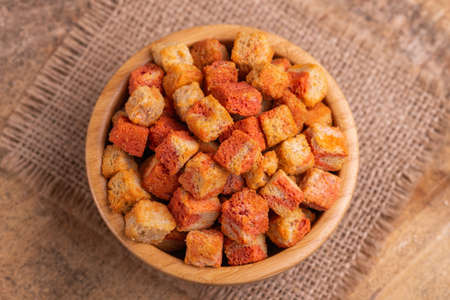 Bacon flavored crackers in wooden bowl on burlap napkin. Beer appetizer. Cinema snack. Copy spaceの写真素材