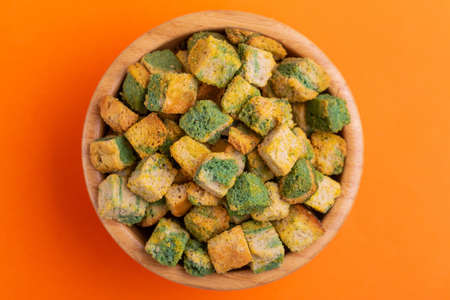 Spinach flavored crackers in wooden bowl on bright colored background. Beer appetizer. Cinema snack. Copy spaceの写真素材