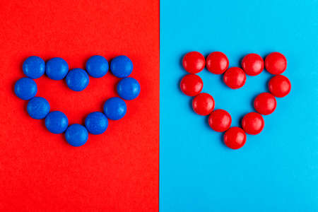 Little glazed chocolate blue and red candies shaped into heart on bright colorful background. Valentine's day. Copy space. Top viewの写真素材