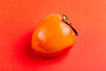 Fresh ripe persimmon fruit on bright red background. Seasonal winter fruit. Copy spaceの写真素材