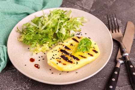 Vegetarian salad with grilled mango, fresh frisee and sesame seeds in plate. Dark concrete background. Healthy food concept.の写真素材