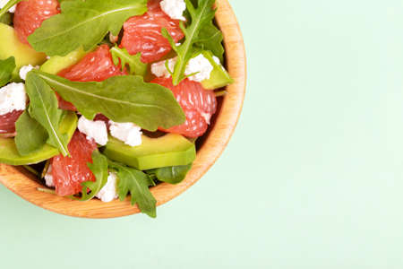 Delicious salad with grapefruit, spinach, feta and avocado in wooden bowl. Healthy food concept. Copy space. Top viewの写真素材