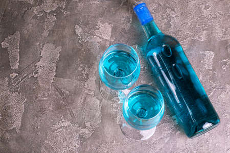 Two glasses and bottle of trendy blue wine. Spanish blue wine chardonnay on dark concrete background. Romantic dateの写真素材