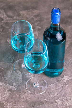 Two glasses and bottle of trendy blue wine. Spanish blue wine chardonnay on dark concrete background. Romantic dateの写真素材