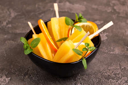Homemade orange ice pop with ripe orange and fresh mint on gray concrete background. Healthy desserts. Lactose free ice cream.の写真素材