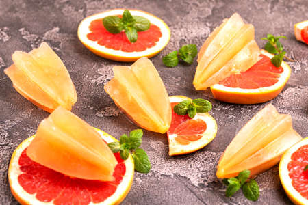 Homemade grapefruit ice pop with ripe grapefruit slices and fresh mint on dark concrete background. Healthy desserts. Lactose free ice creamの写真素材