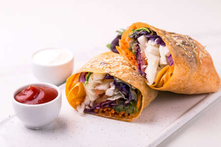 Healthy vegan fried vegetable wrap with salad, arugula, spinach, carrot and cabbage. Vegetarian raw...
