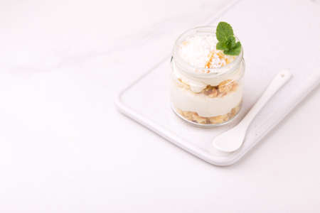Layered coconut bisquit dessert with ricotta, mint and honey in glass jar. Yogurt breakfast