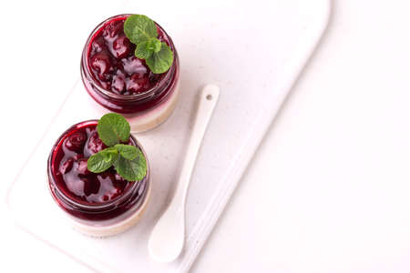 Layered cherry bisquit dessert with ricotta, mint and honey in glass jar. Yogurt cheesecake...