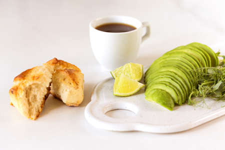 Healthy breakfast with avocado, bun, pea sprouts, lime, pesto and coffee. White background....