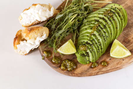Healthy breakfast with avocado, bun, pea sprouts, lime, pesto and coffee. White background....