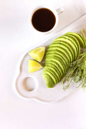Healthy breakfast with avocado, bun, pea sprouts, lime, pesto and coffee. White background. Vegetarian, dietの写真素材