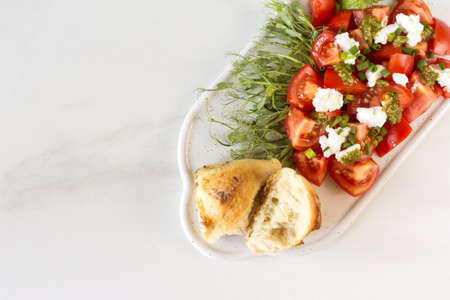 Healthy breakfast salad with tomatoes, avocado, bun, pea sprouts, ricotta, pesto and coffee. White...