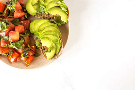 Healthy breakfast toasts with avocado and tomato salad. White background. Vegetarian, diet