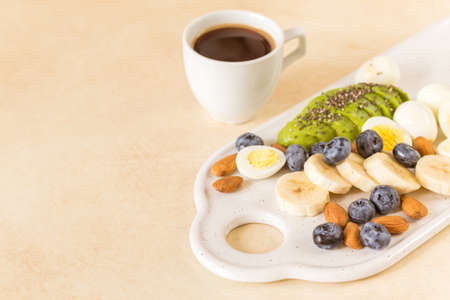 Avocado, boiled quail eggs with banana, blueberry and almond on marble background. Ketogenic diet. Low carb high fat breakfast. Healthy food conceptの写真素材