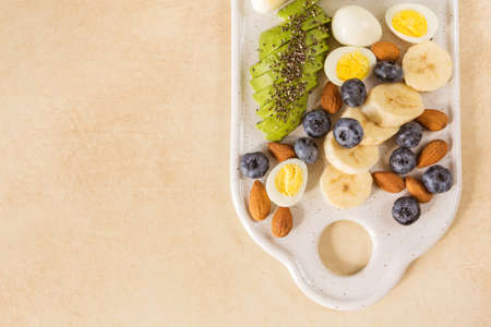 Avocado, boiled quail eggs with banana, blueberry and almond on marble background. Ketogenic diet. Low carb high fat breakfast. Healthy food conceptの写真素材