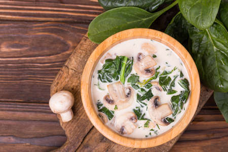 Fresh creamy champignon spinach soup on wooden backgroundの写真素材