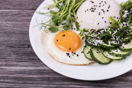 Rice with cucumber, scrambled eggs, microgreen and Japanese wakame seaweed salad. Vegetarian Asian foodの写真素材