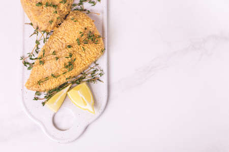 Raw ready to cook chicken breast fillets with breading, lemon and thymeの写真素材