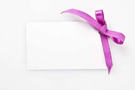 Blank gift tag tied with a bow of satin ribbon  Isolated on white, with soft shadow の写真素材