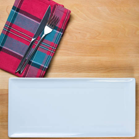 Empty plate with fork and knife on wooden table, table arrangement
