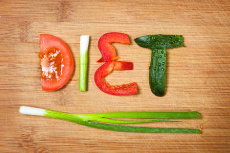 vegetables on the cutting board and word diet over wooden background の写真素材