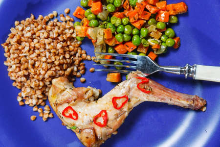 Oven baked rabbit legs with green peas and carrotの写真素材