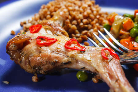 Oven baked rabbit legs with green peas and carrot