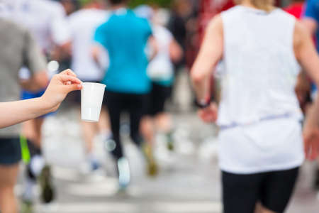 Marathon runner picking up water at service point の写真素材