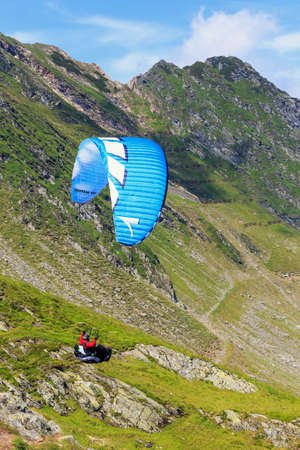 Balea Lake, Romania - JULY 21, 2014: Unidentified paraglider in Balea Lake, Fagaras Mountain, Romania. Paragliding is one of the most popular adventure sports in the worldのeditorial素材