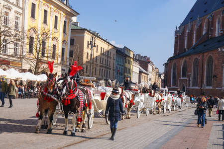 KRAKOW, POLAND - March 07 2015: Unidentified tourists visiting main market square in front of St. Mary's Basilica, in Krakow, Poland on March 07 2015. Old town of Cracow listed as unesco heritage siteのeditorial素材