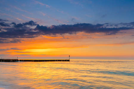 sunset on the beach with a wooden breakwater, long exposureの写真素材
