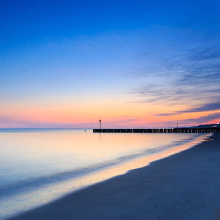sunset on the beach with a wooden breakwater, long exposureの写真素材