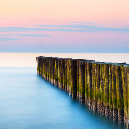 sunset on the beach with a wooden breakwater, long exposureの写真素材
