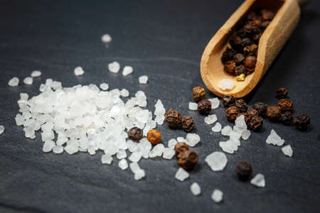 black pepper and salt on rustic stone background. Overhead view food photography.