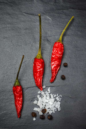 Chili with black pepper and salt on rustic stone background. Overhead view food photography.