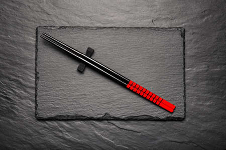Two chopsticks on black stone background with copyspace, top viewの写真素材
